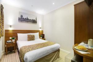 ein Hotelzimmer mit einem Bett und einem Schreibtisch in der Unterkunft Queens Park Hotel in London