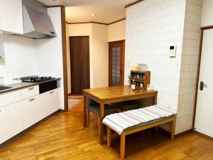 a kitchen with a wooden table and a wooden bench at Nichika House にちか民泊 in Funabashi