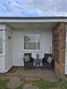 a patio with two chairs and a table at Roma's Retreat chalet, Hemsby in Hemsby