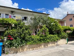 a building with bushes and flowers on a brick wall at Veronika's House in Pula