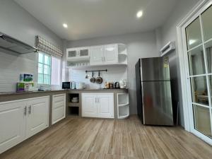 une cuisine avec des armoires blanches et un réfrigérateur en acier inoxydable dans l'établissement Margos Homestay 15mins to MotoGP, à Buriram