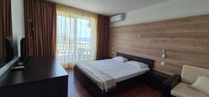 a bedroom with a bed and a desk and a window at Guest House Compass in Lozenets