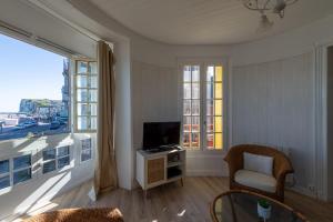 a living room with a tv and a large window at Graziella front de mer in Mers-les-Bains