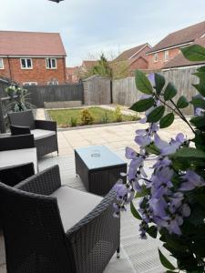 a patio with a table and chairs and purple flowers at Stunning 3 bed house - Wantage in Wantage