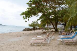 a group of chairs and tables on a beach at Rainbow Paradise Resort by Achlys Collection in Tanjung Bungah