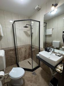 a bathroom with a shower and a toilet and a sink at Hotel Shadervan in Prizren +18 photos