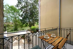 a balcony with a wooden table and a window at Petite Maisonnette at Garitsa! in Corfu International Airport I Kapodistrias