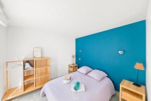 a bed with purple pillows and a blue wall at Maisonnette Saona vue mer plages 800m WiFi CLiM PK By HC in Carqueiranne