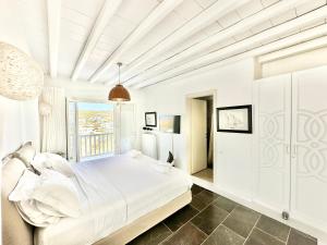 ein weißes Schlafzimmer mit einem Bett und einem Fenster in der Unterkunft Grace Villa Mykonos in Mykonos Stadt + 56 Fotos