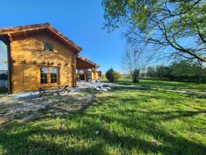 a log cabin with a grassy yard in front of it at Le Chalet « au Fil de l’eau » in Véreux