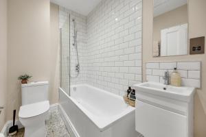 a bathroom with a tub and a toilet and a sink at Hammersmith Flat 2 Bedrooms LGF in London