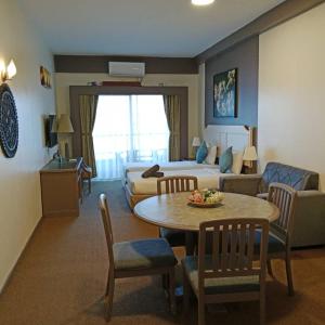 a hotel room with a bed and a table and chairs at Rainbow Paradise BeachFront Penang in Tanjung Bungah