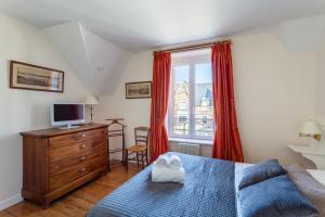 a bedroom with a bed and a tv and a window at Kereden Location in Saint Malo