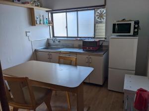 a small kitchen with a table and a refrigerator at Guest house AIZU First in Aizuwakamatsu