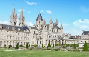 a large castle with a green lawn in front of it at L'Air de Caen in Esquay-Notre-Dame