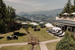 restauracja z krzesłami i parasolami na wzgórzu w obiekcie Gut Berg Naturhotel w mieście Sankt Johann im Pongau