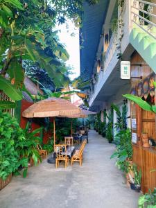 eine Terrasse mit Tischen und Stühlen und einem Sonnenschirm in der Unterkunft Phong lack Guest House in Luang Prabang