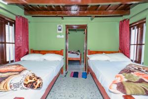 two beds in a room with two windows at Aishwarya Heritage Villa in Vattavada