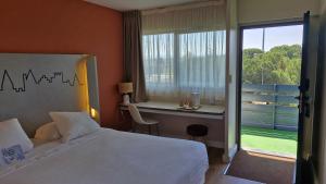 una camera da letto con un letto, una scrivania e una finestra di Kyriad Carcassonne - Aéroport a Carcassonne