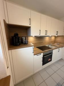a kitchen with white cabinets and a sink at Kleine Auszeit im 1 OG in Heede