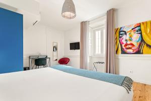 a bedroom with a white bed and a painting on the wall at Jardim da Lapa by Shiadu in Lisbon