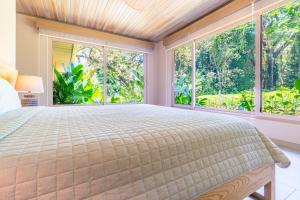 a bedroom with a large bed and large windows at Chalet Tropical - by Pura Villas in Ballena +23 photos