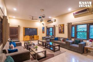 a living room with couches and a flat screen tv at StayVista at Leela Retreat with BBQ, Bonfire, Pool & Lawn in Sohna