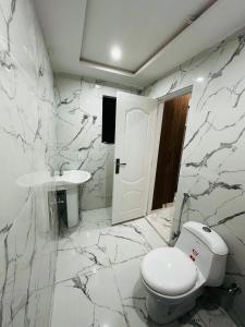 a white bathroom with a toilet and a sink at Urban Apartments in Sialkot