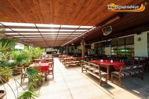 a restaurant with wooden tables and chairs with red table cloth at Хотел Добринище in Dobrinishte
