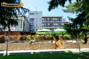 a building with a table and green umbrellas in front at Хотел Добринище in Dobrinishte