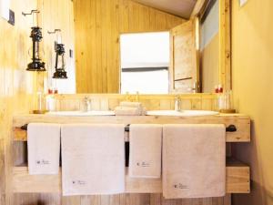 a bathroom with two sinks and a mirror and towels at Serengeti Kifaru Tented Lodge in Mugumu