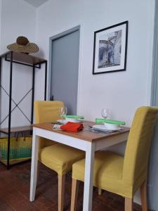 a dining room table with yellow chairs and a wooden table at Les Remparts 1 in La Charité-sur-Loire