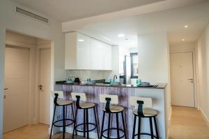 a kitchen with three bar stools and a counter at Apartamento Almunia 2 in Algarrobo-Costa