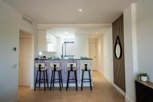 a kitchen with four bar stools in front of a counter at Apartamento Almunia 2 in Algarrobo-Costa +20 photos