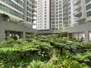 a garden in the middle of a building with tall buildings at Regalia Hostel Free Infinity Skypool Free in Kuala Lumpur