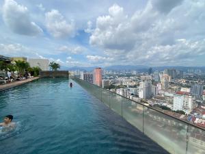 a man swimming in a infinity pool on top of a building at Regalia Hostel Free Infinity Skypool Free in Kuala Lumpur