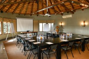 a conference room with tables and chairs and a screen at The Springbok Lodge in Nambiti Private Game Reserve