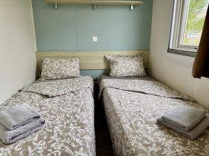zwei Betten in einem kleinen Zimmer mit Fenster in der Unterkunft Un toit sur le bassin bungalow camping les viviers in Lège-Cap-Ferret