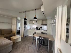 eine Küche und ein Wohnzimmer mit Tisch und Stühlen in der Unterkunft Un toit sur le bassin bungalow camping les viviers in Lège-Cap-Ferret