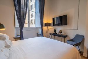 ein Schlafzimmer mit einem weißen Bett, einem Stuhl und einem TV in der Unterkunft Maison Luxury Suite - Duomo in Florenz