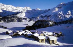 a village covered in snow in front of a mountain at Hotel Cristallina in Sils Maria