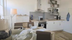 a kitchen with a table and chairs and a kitchen with white cabinets at Westwind - schöne neue 2-Zi Whg 37qm für 1-4 Pers in Juist +4 photos