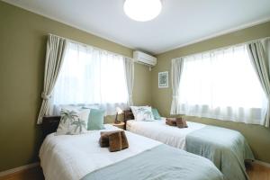 two beds in a room with two windows at Terumare in Uruma