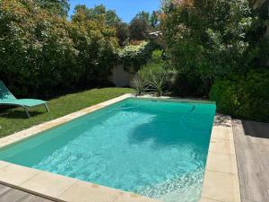 a swimming pool in a yard with a chair at Les Jardins du Castelas - Domaine et Spas in Uchaux