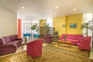 a living room with pink couches and a tv at Nefeli Hotel in Athens