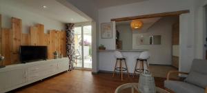 a living room with a tv and a kitchen with a counter at Famara - Casa Marosenia in Güime