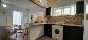 a kitchen with a washer and a sink and a washing machine at Famara - Casa Marosenia in Güime +7 photos