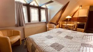 ein Schlafzimmer mit einem Bett und 2 Stühlen sowie eine Küche in der Unterkunft Cafe Gaubenhaus in Bad Fallingbostel