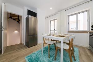 a kitchen and dining room with a white table and chairs at Casinha da Rosa in Nazaré