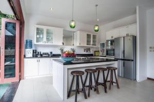a kitchen with white cabinets and a island with bar stools at Villa Annecy in Seminyak